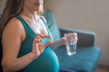Pregnant woman taking omega-3 DHA capsule