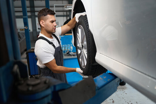 Young male changing car wheel in tire fitting