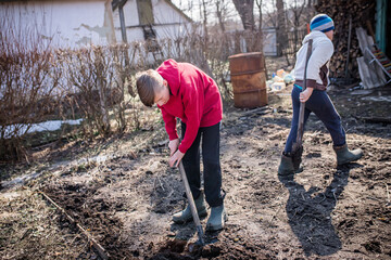 Two brothers of a farmer are digging a vegetable garden in the backyard near a house in a village...