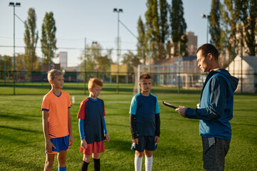 Fototapeta premium Young soccer coach teaching kids on football field