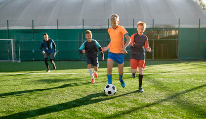 Young boys playing soccer game during junior competition at sport school