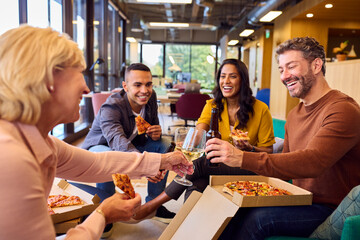 Staff At Informal Meeting In Office With Takeaway Pizza And Drinks
