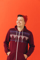 Young man in Christmas sweater and hat on color background.