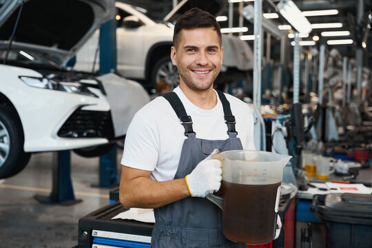 Smiling male holding engine oil and looking at the camera