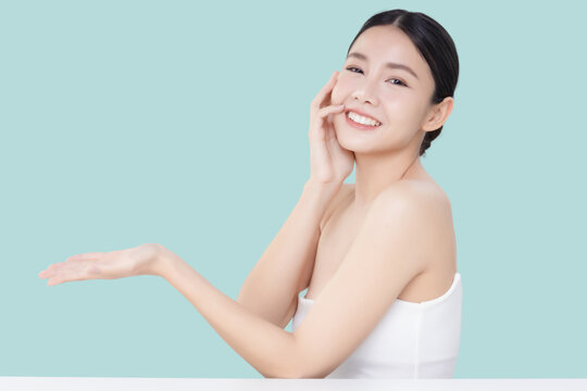 Studio shot Beautiful young Asian woman with clean fresh skin open hand isolated on blue background, Face care treatment beauty and spa concept.