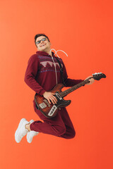 A young man in a Christmas kigurumi plays an electric guitar on a colored background.