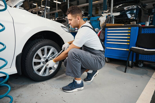 Handsome male changing car wheel in tire fitting