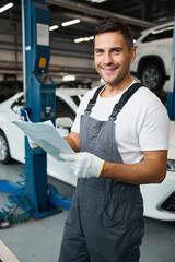 Male checking car documents during car repiar