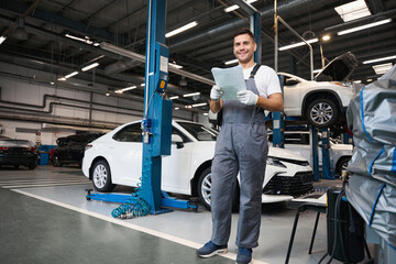 Worker checking car documents during car repiar