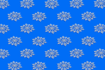 Winter pattern made of white snowflakes on bright blue background. Christmas and new year celebration concept. Holiday theme