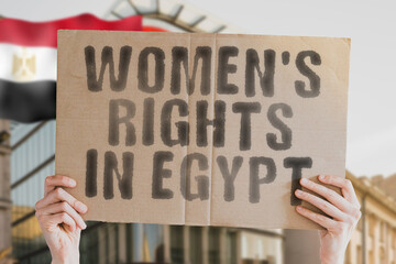 The phrase " Women's rights in Egypt " is on a banner in men's hands with blurred background. Cheering. Community. Confidence. Courage. Crowd. Defend. Determination. Different. Diversity. Fight
