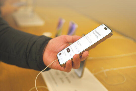 customer testing new iPhone in apple sales office in Germany, products and accessories modern retail store with exhibition gadgets, samples, people, buyers came to buy, Frankfurt - December 2022