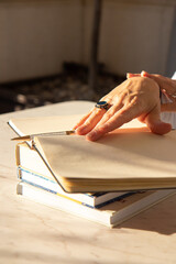Woman writing in a notebook placed on a bright desktop in the sun. Education concept