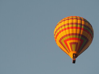 Fototapeta premium Hot air balloons over a blue sky background positioned at the right side of the image. Yellow balloons against the sky at Laos, Vang Vieng. 