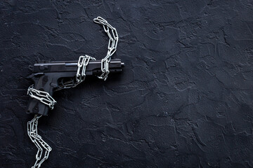 Fototapeta na wymiar Black gun weapon in chains. Illegal use of weapons concept