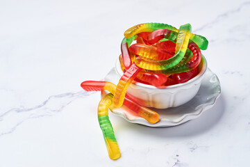 Colored gummy worms in a bowl.