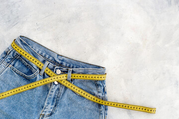 Weight loss concept. Jeans with yellow measuring tape instead of a belt