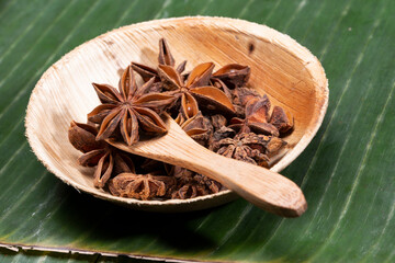 Asterisk on wooden spoon with green banana leaf background.
