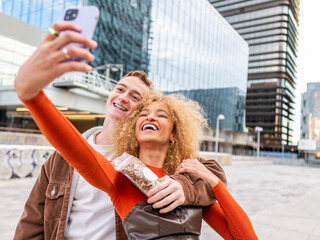 Happy young diverse couple taking selfie on street