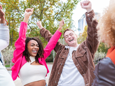 Positive Young Diverse Friends With Raised Arms Smiling Happily On Street