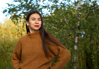 Positive woman with charming smile looks into camera. Girl in brown outfit posing on park in spring