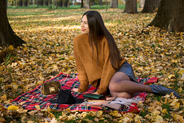 Fall picnic on september. Young woman resting in nature on blanket with book and diary. Autumn mood. People, lifestyle, relaxation and vacations on nature concept.