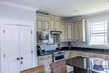A cream colored new construction kitchen with black granite countertops and wood flooring and stainless steel appliances