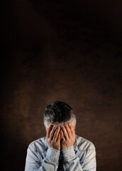 portrait d'un homme de 50 ans qui met ses mains sur son visage en signe de fatigue ou de tristesse. concept de dépression et de solitude. Large place pour le texte.