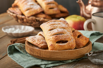 Hand pies. Mini puff pastry or hand pies stuffed with apple and sprinkle sugar powder in wooden plate. Homemade pie snack with crust for breakfast rustic photo.  Copy space.
