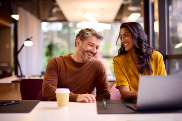 Male And Female Business Colleagues Meeting Around Laptop In Modern Office