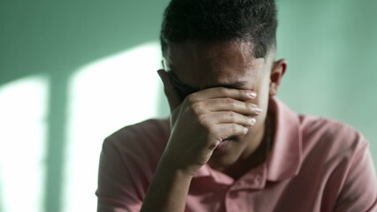 Desperate young man feeling hopeless and despair. A hispanic South American person crying covering face with hand 2