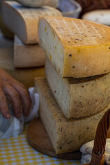 Craft cheese at the fair sale on the counter in November. Farmers market presents the products of private cheese factory. Selective focus, shallow detph of field
