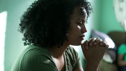 A hopeful Brazilian young woman praying at home. An African South American person having FAITH