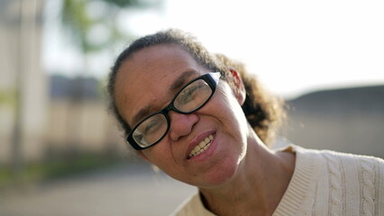 Portrait of a happy mature hispanic woman standing outdoors in sunlight. South American latin older...