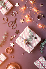 Dark brown Christmas background with wrapped Xmas gifts. Monochromatic flat lay with marzipan sweets, wrapped gift boxes, eucalyptus, nuts, stars, cinnamon buns. Paper top view with snowflakes and