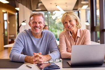 Portrait Of Mature Male And Female Business Colleagues Meeting Around Laptop In Modern Office