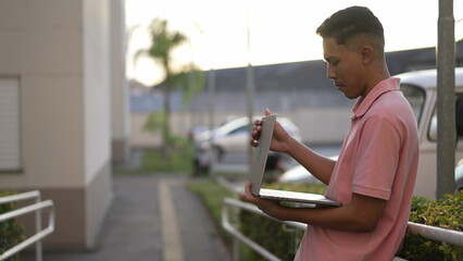 One young hispanic man shutting laptop off. Male person turning computer putting modern device away. Guy closing screen 2