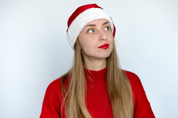 Thoughtful look of a girl in a Santa hat and a red sweater.