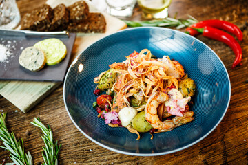 Warm salad with Argentinian king prawns. Almond potato, mini romaine lettuce, carrot, cherry tomato, pesto, black root chips, caramelized walnut, beet balsamic. Food served in modern restaurant