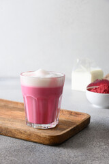 Beetroot latte of beet powder in glass servwd on wooden tray. Trendy healthy vegan and caffeine free drink. Vertical format.