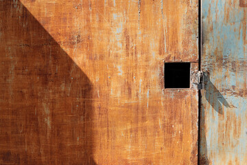 abstract background, black square hole on old galvanized door with a key lock for delivering small items