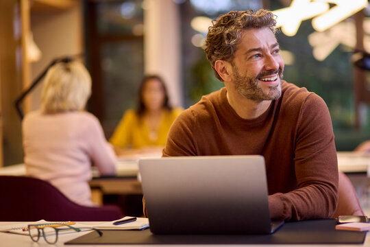 Mature Businessman Working On Laptop At Desk In Office