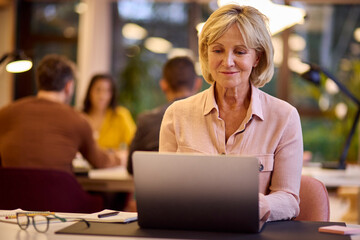 Mature Businesswoman Working On Laptop At Desk In Office
