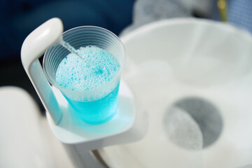 Glass with disinfectant solution for by patient in modern dental office