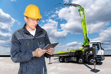Engineer with digital tablet on a background of truck-mounted concrete pump