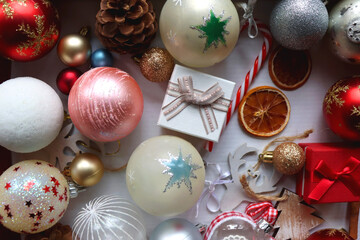 Various colorful Christmas ornaments, small presents and seasonal spices in a white box. Top view.