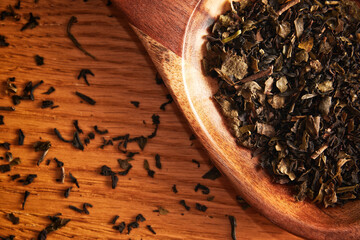 Flat lay template with scattered tea leaves and wooden spoon on the table. Food and spices theme
