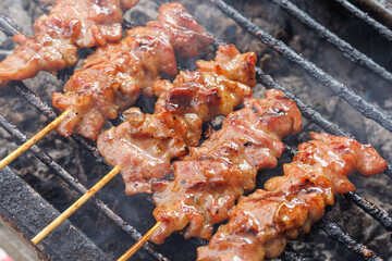 Grilled pork skewers on the stove with smoke. Traditional Thai-style grilled pork. Delicious and...