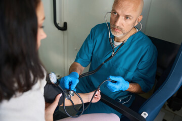 Man in a medical uniform measures the pressure of patient