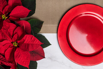 Christmas poinsettia with red plate placemat on gold placemat marble background